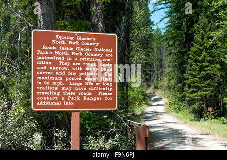 Ein Warnsignal über das fahren auf den Nebenstraßen im Bereich North Fork des Glacier National Park, mit einem Feldweg im Hintergrund. Stockfoto