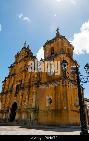 Alte Laterne vor gelbe Kirche mit White Uhr und eine Glocke an der Spitze unter blauem Himmel Stockfoto