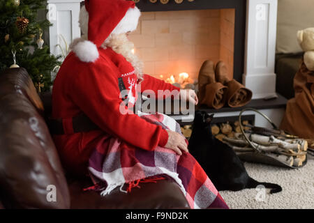 Santa Claus Erwärmung Fütterung seiner Katze zu Hause Stockfoto