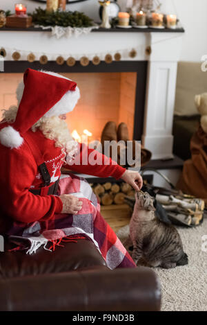 Santa Claus Erwärmung Fütterung seiner Katze zu Hause Stockfoto