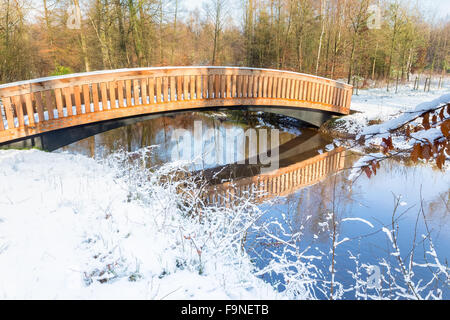 Hölzerne Fußgängerbrücke mit Schnee und Wasser in Winterlandschaft Stockfoto