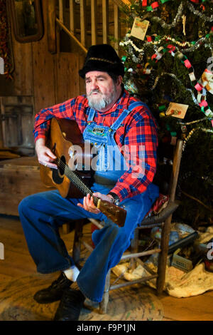 Musiker spielt Gitarre Weihnachtsbaum in einer Blockhütte am Museum von den Appalachen, Tennessee, USA. Stockfoto