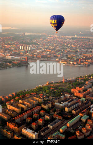 Heißluft-Ballon schwebt über Södermalm und Inseln von Stockholm mit dem Rathaus in Riddarfjarden Gewässern bei Sonnenuntergang Stockfoto