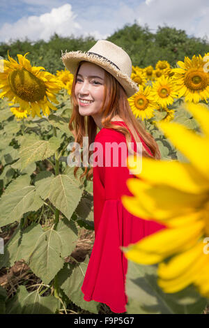 schöne Frau glücklich und genießen Sie im Sonnenblumenfeld Stockfoto