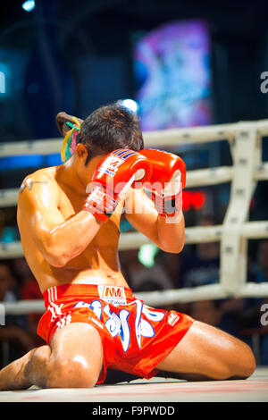 Männliche Muay thai Kickboxer kniend und bedeckte sein Gesicht mit Handschuhen während der traditionellen vor dem Kampf Ritual namens Wai khru Stockfoto