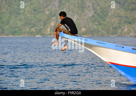 Mann sitzen und Relaxen an der Vorderseite ein Holzboot Stockfoto