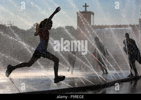 Jugendliche durch Wasserfontänen Spritzen aus springen Feuerwehrschläuche zur Abkühlung an einem heißen Sommertag während 35.. Deutschen Evangelischen Kirchentag in Stuttgart, Deutschland, 5. Juni 2015 Stockfoto