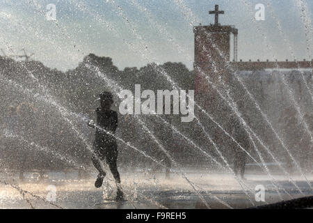 Jugendliche durch Wasserfontänen Spritzen aus springen Feuerwehrschläuche zur Abkühlung an einem heißen Sommertag während 35.. Deutschen Evangelischen Kirchentag in Stuttgart, Deutschland, 5. Juni 2015 Stockfoto