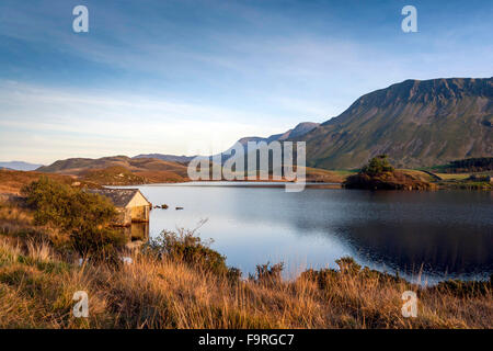 Ein Bootshaus auf der Seite Cregennan Seen gebadet in späten Herbstsonne mit einem Hintergrund von Cader Idris und sanften Hügeln. Stockfoto