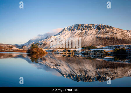 Die Winter tief verschneiten Hänge des Gebirges Cader Idris spiegeln sich im ruhigen Wasser der Cregennen Seen. Stockfoto