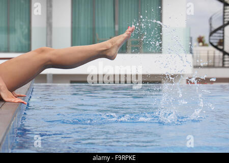 Junge schöne Frau, so dass Spritzwasser mit Beinen am pool Stockfoto