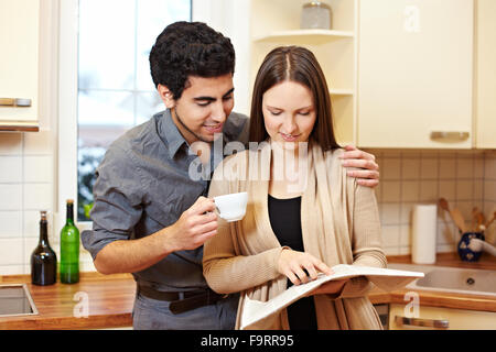 Junges Paar Lesen einer Zeitung zusammen in der Küche Stockfoto