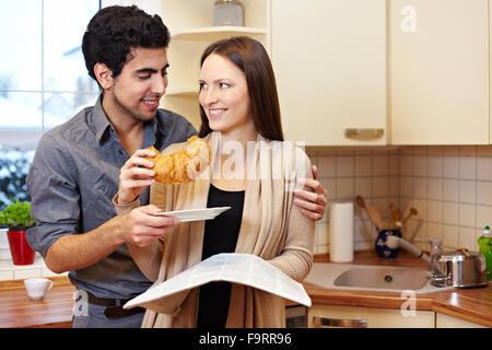 Glückliches Paar in eine Küche teilen Croissang und Zeitung Stockfoto