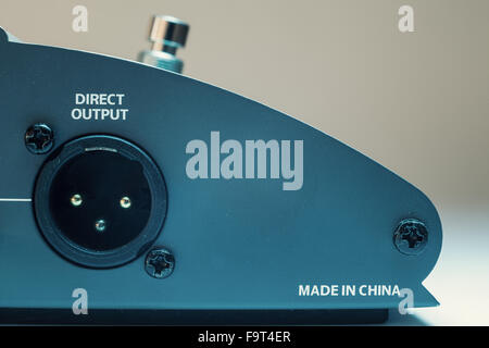 Konzeptuelle Komposition über die Produktion in China, Teil einer Gitarre pedal, Detailansicht auf Output und Text. Stockfoto