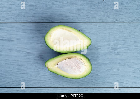 Reife grüne Avocado auf blauen Holztisch Stockfoto