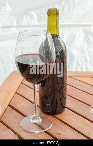 Einzelne Flasche Rotwein und Glas auf Tisch Stockfoto