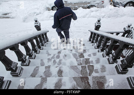 USPS Lieferung Mann geht auf einer Schnee bedeckten Sandsteinhaus Stadthaus Stoop nach Abgabe eines Pakets Stockfoto