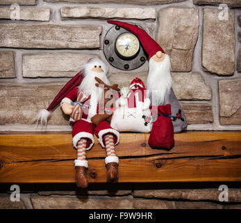 Zwei Weihnachtsmänner und Schneemann unter der Uhr auf dem Kamin sitzen. Weihnachts-Dekoration. Stockfoto