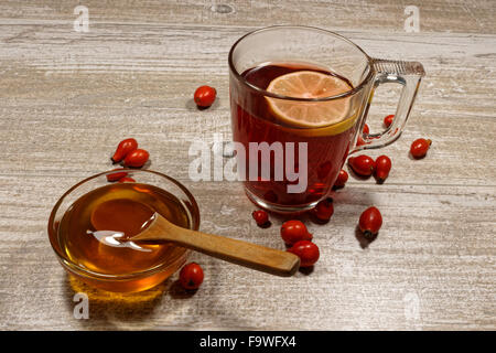 Hagebutten Tee mit Honig und Zitrone auf Holztisch Stockfoto