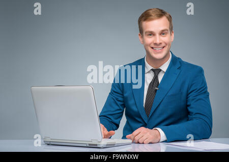 Lächelnde Zeitungsmann arbeitet mit seinem Laptop. Stockfoto