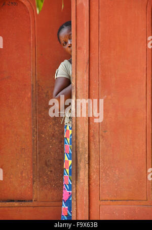 Frauen, die hinter Tür ihres Hauses, Lome, Togo herausschauen Stockfoto