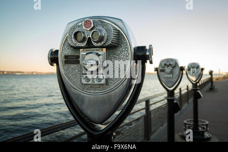 Nach unten eine Reihe von Ferngläser oder Teleskope weiter zum Fluss bei Sonnenuntergang an einem klaren Tag auf Liberty Island, NYC Stockfoto