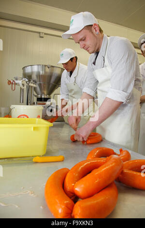 Metzger bei der Wurst-Maschine macht Würstchen aus Schweinefleisch. Stockfoto