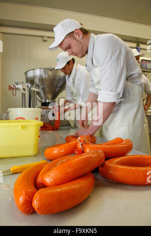 Metzger bei der Wurst-Maschine macht Würstchen aus Schweinefleisch. Stockfoto