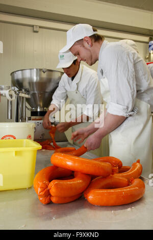 Metzger bei der Wurst-Maschine macht Würstchen aus Schweinefleisch. Stockfoto