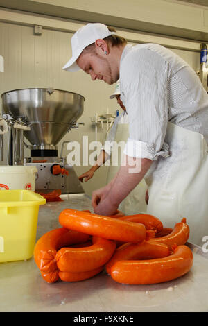 Metzger bei der Wurst-Maschine macht Würstchen aus Schweinefleisch. Stockfoto