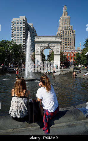 Besucher entspannend am zentralen Brunnen im Washington Square Park mit Washington Square Arch im Hintergrund, New York City Stockfoto