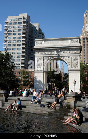 Besucher entspannend am zentralen Brunnen im Washington Square Park mit Washington Square Arch im Hintergrund, New York City Stockfoto