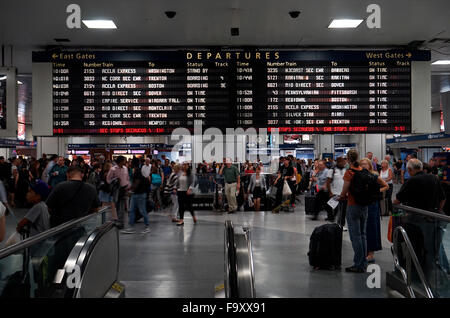 Menschen innerhalb der Penn Station mit Abreise Informationsbildschirm im Hintergrund. Manhattan, New York City, USA Stockfoto