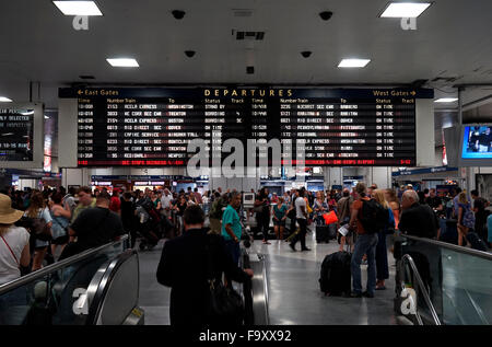 Menschen innerhalb der Penn Station mit Abreise Informationsbildschirm im Hintergrund. Manhattan, New York City, USA Stockfoto