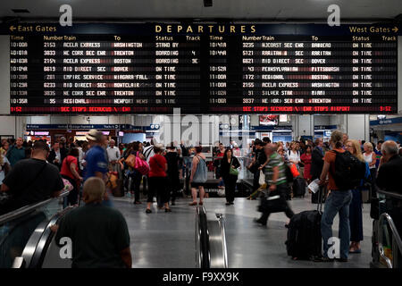 Menschen innerhalb der Penn Station mit Abreise Informationsbildschirm im Hintergrund. Manhattan, New York City, USA Stockfoto