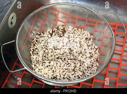 Nassen Quinoa und Basmati Reis in einem Metallsieb in der Küchenspüle Stockfoto