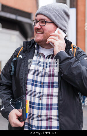Ein junger Mann mit Brille suchen herum und Lachen mit einer Karte und einem mobilen Gerät in einer urbanen Szene hat er eine interessante exp Stockfoto