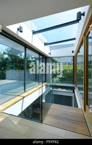 Das Innere eines modernen Hauses an der Küste. Große Glas-Schiebetüren öffnen. Boden bis zur Decke Glasscheiben. Ein flaches Gebäude in einer Lage direkt am Meer.  Ein Blick auf das Meer. Stockfoto