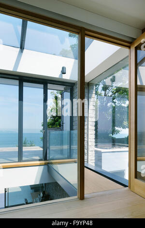 Die Innenräume von einem modernen Haus auf den Klippen mit Blick aufs Meer. Große Glasflächen und Stadtmauern und Holzregale und Raumteiler. Stockfoto