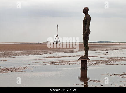 Crosby Strand: eines der Eisen-Männer, mit an einem anderen Ort von Antony Gormley, verleiht eine ikonische Vordergrund Crosby Strand Stockfoto