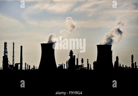 Rauch und Dampf, die sich aus petrochemischen Industrieanlagen Schornsteine Silhouette gegen den Himmel Stockfoto