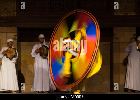 Ägyptischer Sufi-Tänzer in gelb Spinnen eine bunte Runde Blatt während tanzender Derwisch bei offenen Innenhof Luftleistung Stockfoto