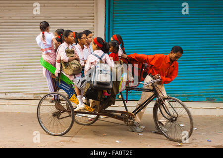 Junge Mädchen drängten sich in einen überladenen private Fahrradrikscha Reiten unangenehm zur Schule am Morgen Stockfoto