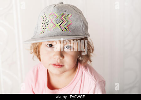 Closeup Portrait von niedlichen kaukasischen blonde Baby Mädchen in rosa T-shirt und graue Mütze Stockfoto