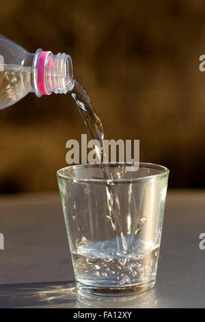 Wasser aus PET-Flasche in ein Glas gießen Stockfoto