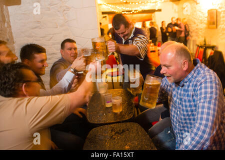 Eine Gruppe von Männern, die Bier trinken und Lager aus Glas "Bierkrüge" bei einer deutschen Themen Bavarian Stompers Party-Nacht in einer Kneipe, Wales UK Stockfoto