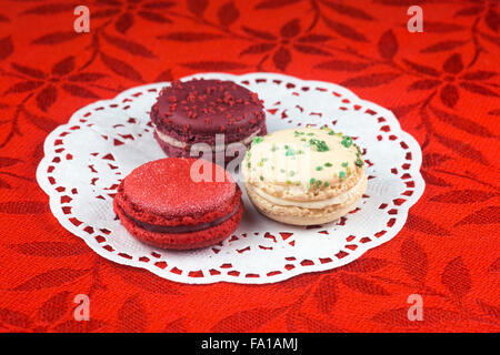 Weihnachten Macarons, Vanille, Basilikum, Matt Cranberry und Glühwein Weine Aromen auf roten Tischdecke Stockfoto