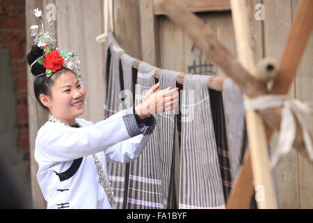 Qiandongnan, Chinas Provinz Guizhou. 19. Dezember 2015. Eine Frau Dong ethnischen Gruppe lüftet das handgewebte Tuch in Lexiang Dorf von Rongjiang County, Südwesten Chinas Provinz Guizhou, 19. Dezember 2015. Das handgefertigte Tuch dient hauptsächlich von einheimischen Trachten Dong ethnischen Gruppe zu machen. © Wu Jibin/Xinhua/Alamy Live-Nachrichten Stockfoto