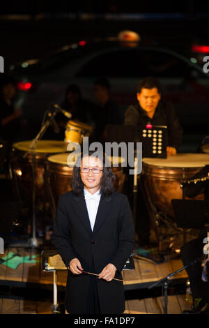 Langhaarige nicht identifizierten Dirigent eines Symphonieorchesters akzeptiert Applaus im Rampenlicht bei einem Sommer-Nacht-Konzert Stockfoto