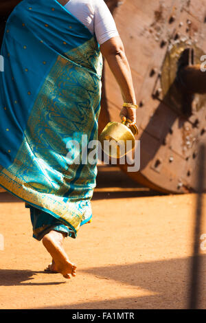 Indische Frau in grünen Sari tragen einen goldenen Metall Krug vorbei an der großen Ratha Wagen-Räder Stockfoto